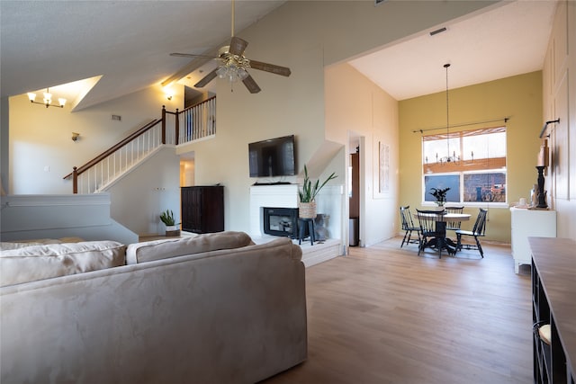 living room featuring ceiling fan with notable chandelier, high vaulted ceiling, and hardwood / wood-style floors