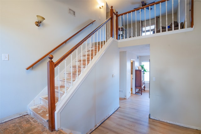 staircase featuring wood-type flooring and a high ceiling