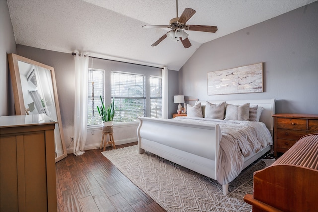 bedroom featuring dark hardwood / wood-style flooring, ceiling fan, vaulted ceiling, and a textured ceiling