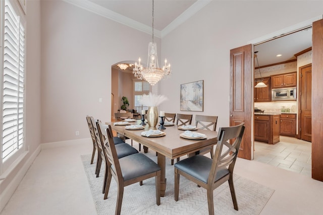 dining area with a notable chandelier, ornamental molding, high vaulted ceiling, and plenty of natural light