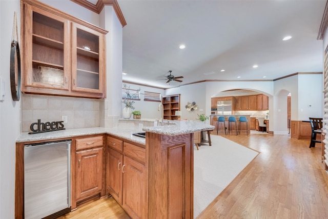 kitchen with light stone countertops, sink, light wood-type flooring, and kitchen peninsula