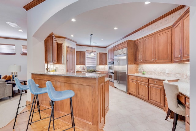 kitchen featuring a breakfast bar, decorative light fixtures, kitchen peninsula, stainless steel appliances, and light stone countertops