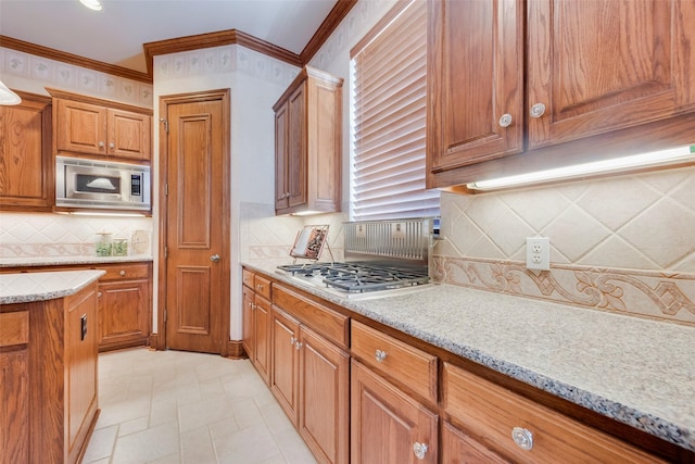 kitchen with light stone counters, appliances with stainless steel finishes, crown molding, and decorative backsplash