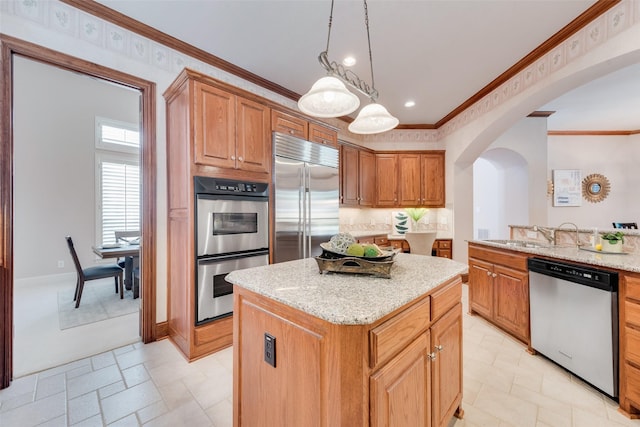 kitchen with a kitchen island, sink, ornamental molding, light stone counters, and stainless steel appliances