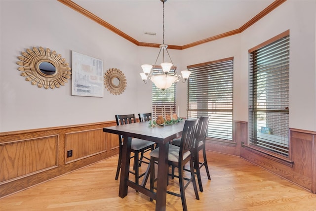 dining space with ornamental molding, a chandelier, and light wood-type flooring