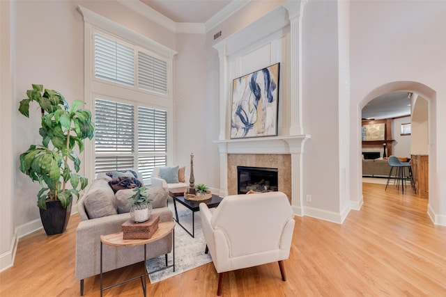 living room featuring crown molding, light hardwood / wood-style flooring, and a high ceiling