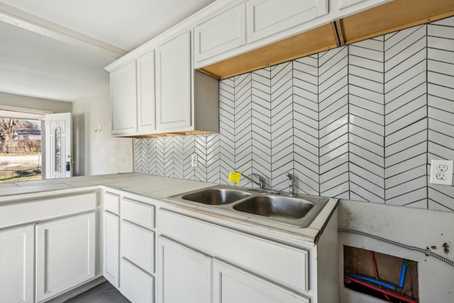 kitchen featuring sink, decorative backsplash, and white cabinets