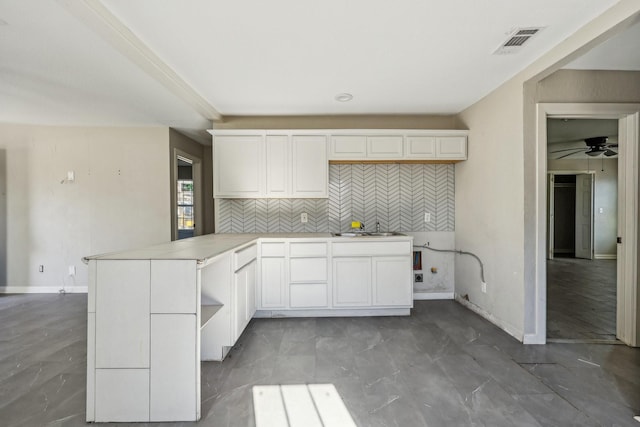 kitchen featuring sink, white cabinetry, kitchen peninsula, ceiling fan, and backsplash