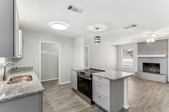 kitchen featuring pendant lighting, sink, stainless steel electric range, light stone countertops, and light hardwood / wood-style floors