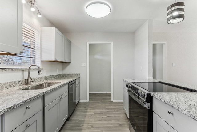 kitchen with sink, gray cabinets, appliances with stainless steel finishes, light stone countertops, and light wood-type flooring