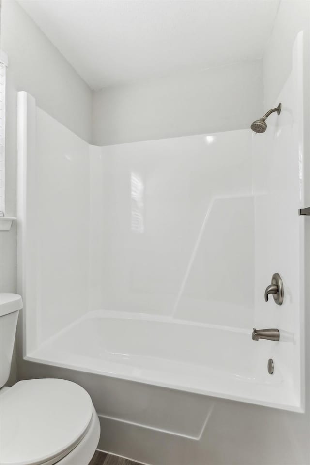 bathroom with wood-type flooring, bathing tub / shower combination, and toilet