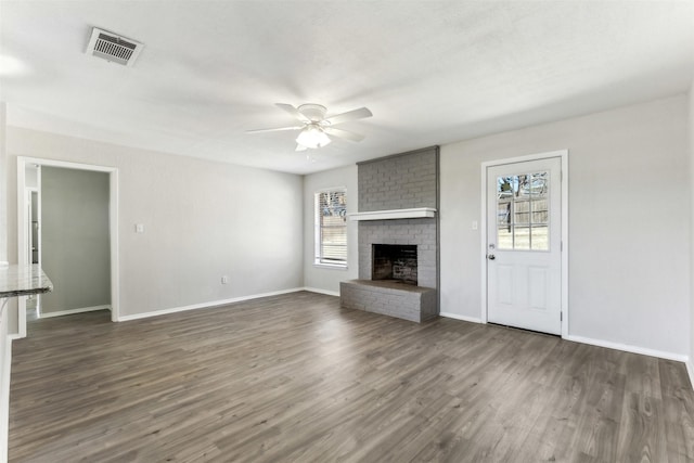 unfurnished living room featuring ceiling fan, a fireplace, plenty of natural light, and dark hardwood / wood-style flooring