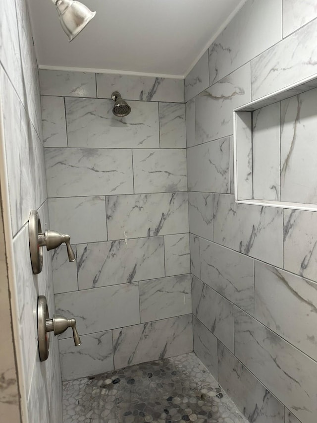 bathroom with a tile shower and crown molding