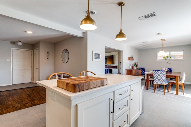 kitchen featuring hanging light fixtures, a kitchen island, light tile patterned floors, and white cabinets