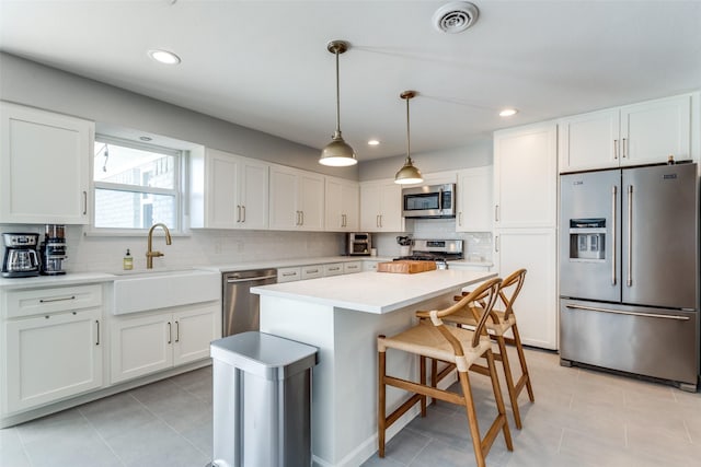 kitchen featuring sink, white cabinetry, decorative light fixtures, a kitchen island, and stainless steel appliances