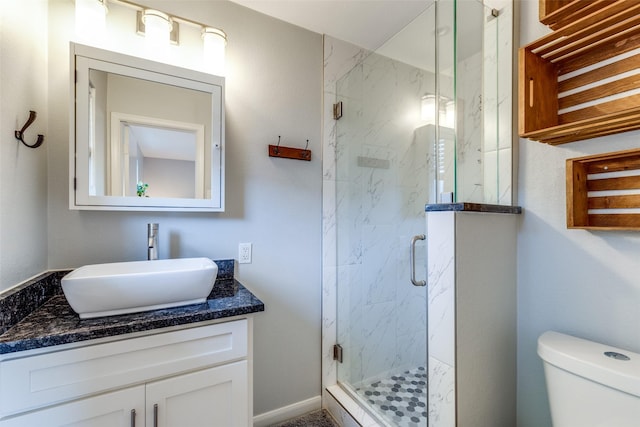 bathroom featuring vanity, a shower with shower door, and toilet