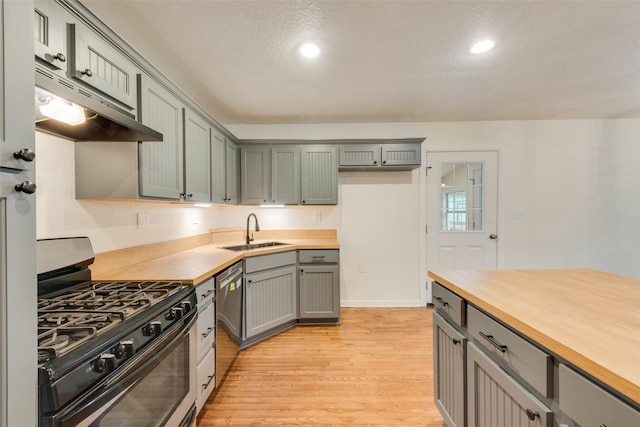 kitchen featuring stainless steel appliances, butcher block counters, sink, and light wood-type flooring