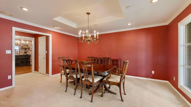 carpeted dining area with a tray ceiling, a notable chandelier, and crown molding