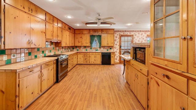 kitchen with tile countertops, black appliances, decorative backsplash, ceiling fan, and light hardwood / wood-style floors