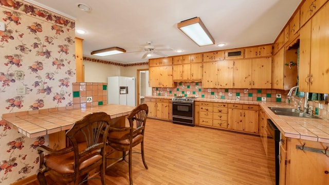 kitchen featuring sink, stainless steel stove, tile counters, white fridge with ice dispenser, and kitchen peninsula