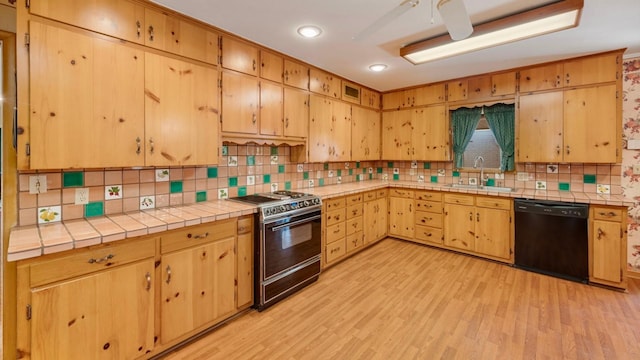 kitchen featuring light hardwood / wood-style floors, range, black dishwasher, and sink