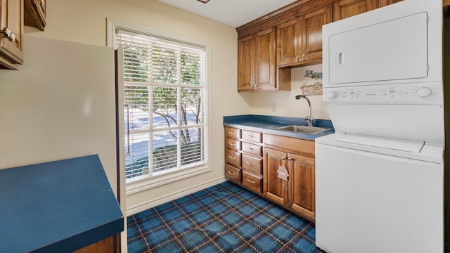 laundry room featuring sink, cabinets, and stacked washer / dryer