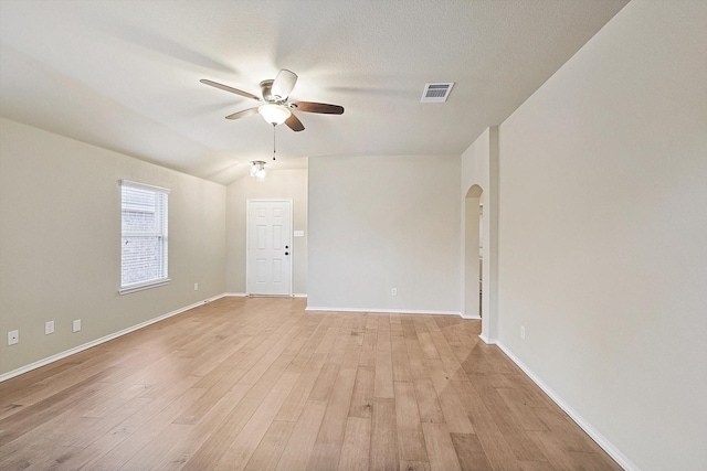 empty room with lofted ceiling, a textured ceiling, ceiling fan, and light wood-type flooring