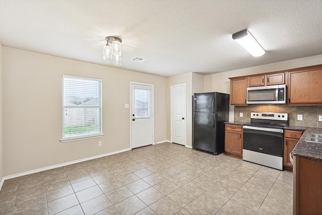 kitchen with light tile patterned floors, decorative backsplash, stainless steel appliances, and a textured ceiling