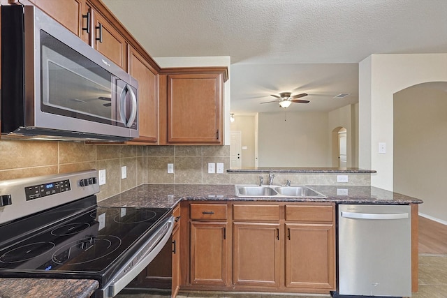 kitchen featuring stainless steel appliances, tasteful backsplash, sink, and dark stone counters