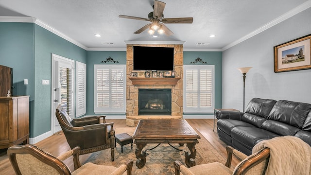 living room with ornamental molding, ceiling fan, a fireplace, and light hardwood / wood-style flooring