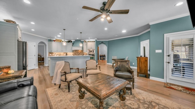 living room featuring ceiling fan, crown molding, and light hardwood / wood-style floors