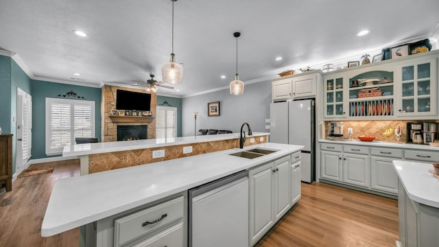 kitchen with sink, dishwasher, hanging light fixtures, an island with sink, and white cabinets