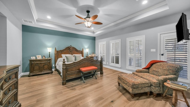 bedroom with crown molding, ceiling fan, a raised ceiling, and light hardwood / wood-style flooring