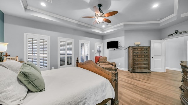 bedroom with crown molding, wood-type flooring, a raised ceiling, and ceiling fan