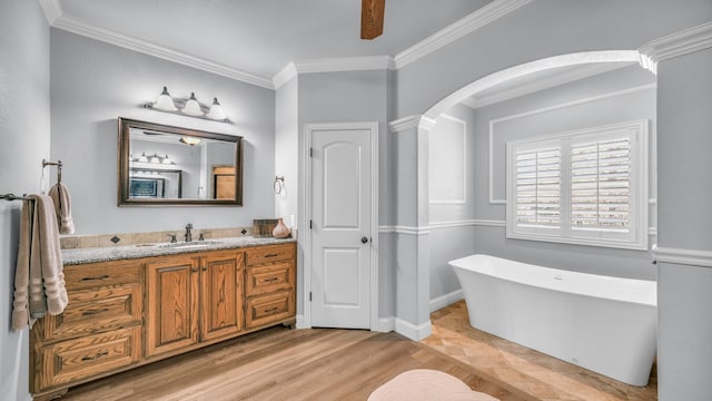 bathroom featuring crown molding, hardwood / wood-style flooring, ceiling fan, vanity, and a bath