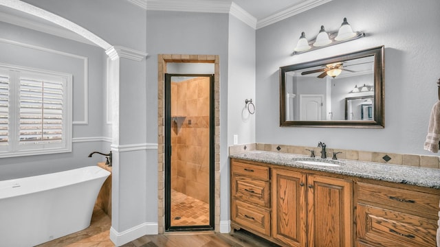 bathroom with plus walk in shower, wood-type flooring, ornamental molding, vanity, and ceiling fan