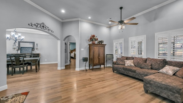 living room with crown molding, light hardwood / wood-style floors, ceiling fan, and a towering ceiling