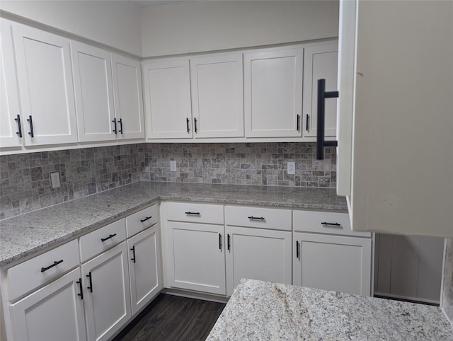 kitchen with white cabinetry, light stone counters, and backsplash