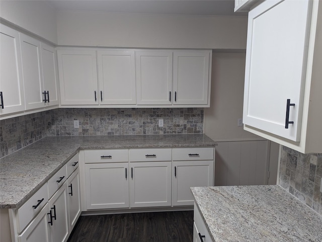 kitchen with white cabinetry, tasteful backsplash, dark hardwood / wood-style flooring, and light stone counters