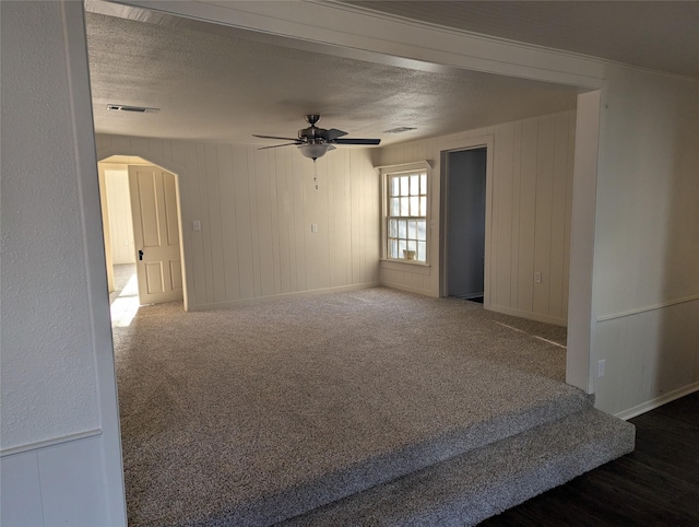 carpeted empty room with ceiling fan and a textured ceiling