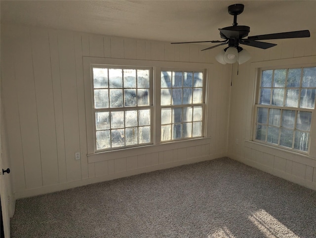 empty room featuring ceiling fan, plenty of natural light, and carpet floors