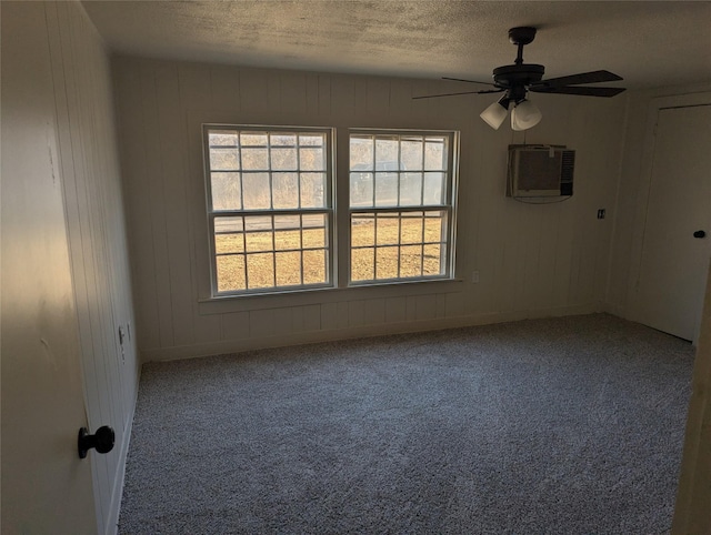 spare room with a wall mounted air conditioner, carpet floors, a textured ceiling, and a wealth of natural light