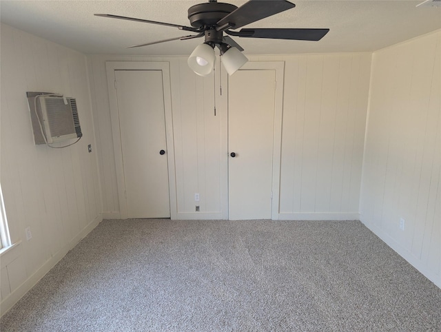 unfurnished bedroom with ceiling fan, a wall mounted AC, carpet, and a textured ceiling