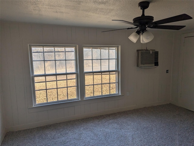 carpeted empty room with ceiling fan, a textured ceiling, a wall mounted AC, and a healthy amount of sunlight