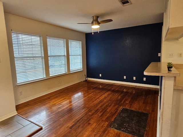 unfurnished dining area with ceiling fan and dark hardwood / wood-style flooring