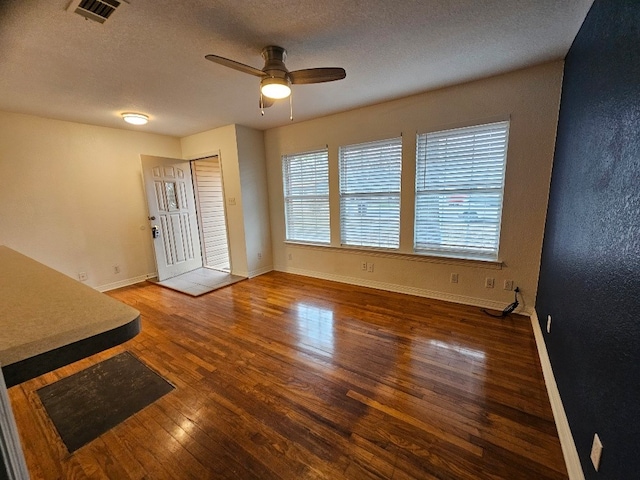 unfurnished living room with ceiling fan, dark hardwood / wood-style floors, and a textured ceiling