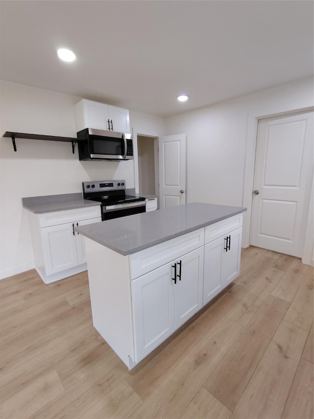 kitchen with light wood finished floors, open shelves, appliances with stainless steel finishes, and white cabinetry