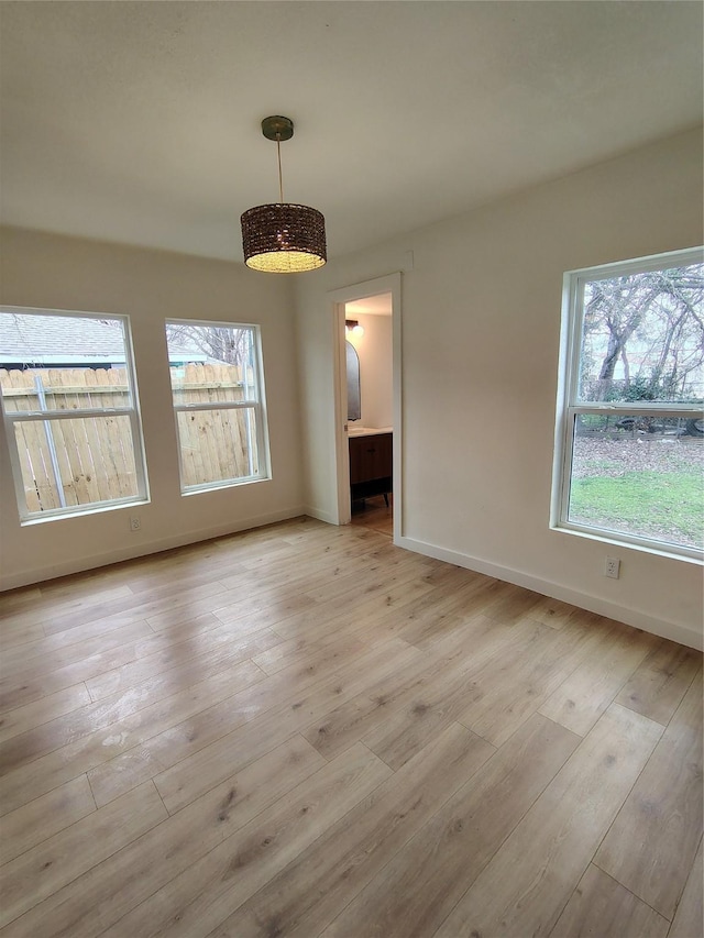 unfurnished dining area featuring light wood-style flooring and baseboards