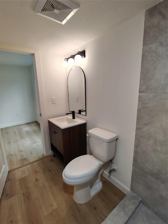 bathroom featuring toilet, wood finished floors, vanity, visible vents, and baseboards