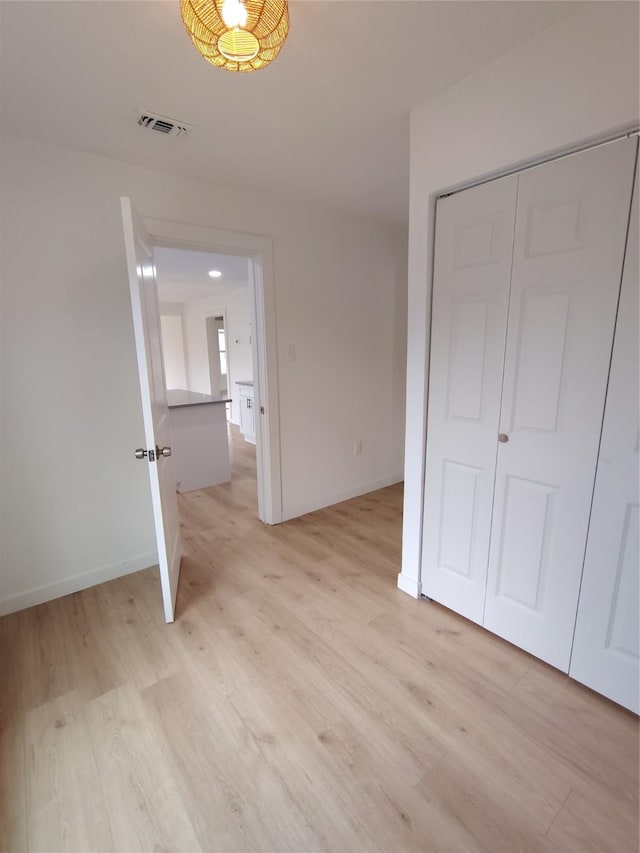 unfurnished bedroom featuring baseboards, visible vents, and light wood finished floors